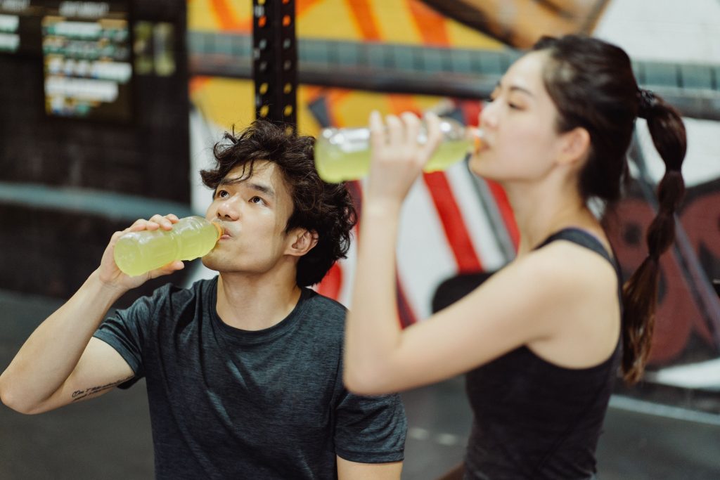 Athletes drinking an electrolyte drink after a workout at the gym